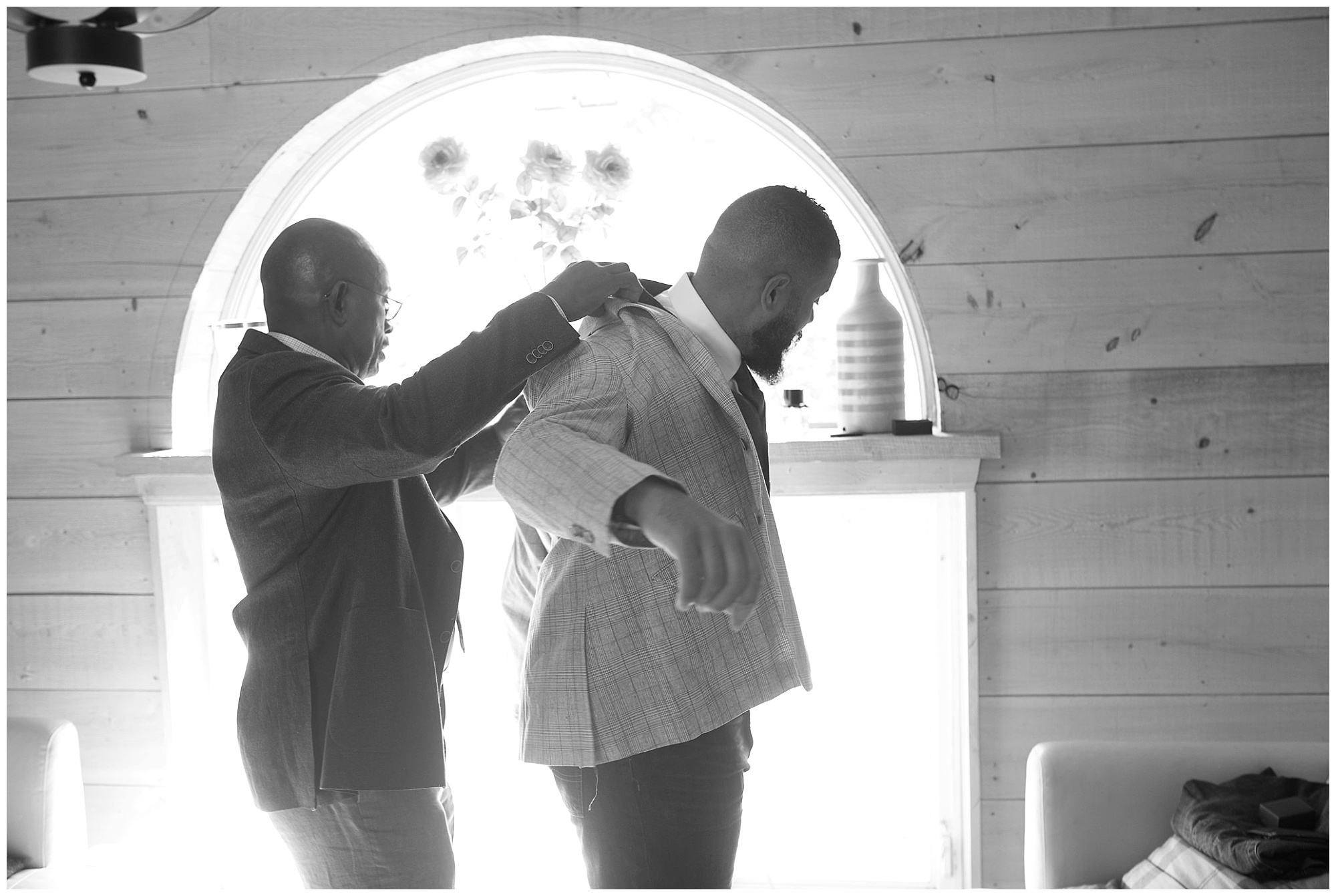 Photo if grooms dad helping groom put on suit jacket