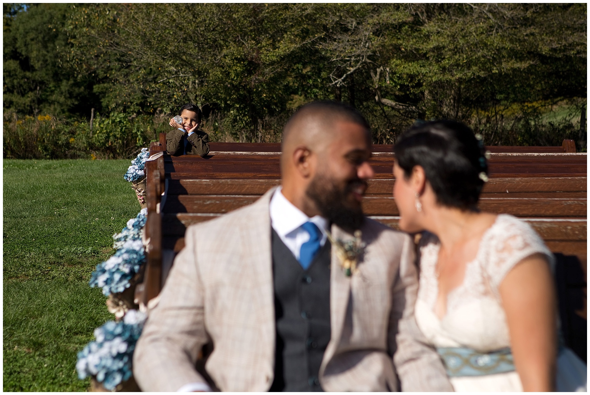 Young boy photobombing this bride and groom's photo in a very cute fashion.