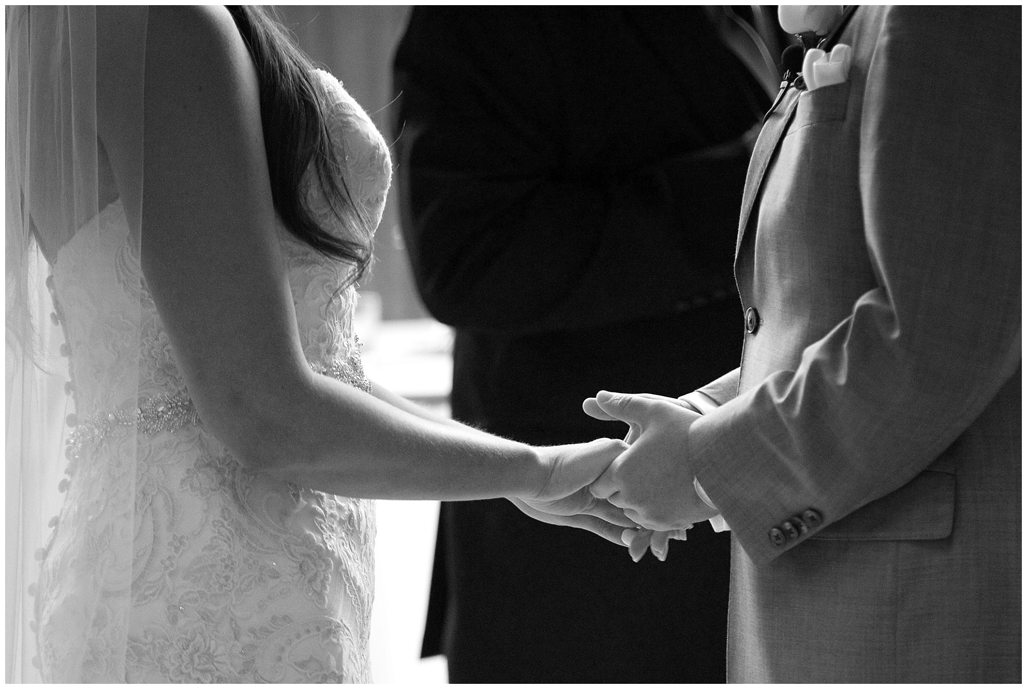 Photo of a bride and groom holding hand during their ceremony.