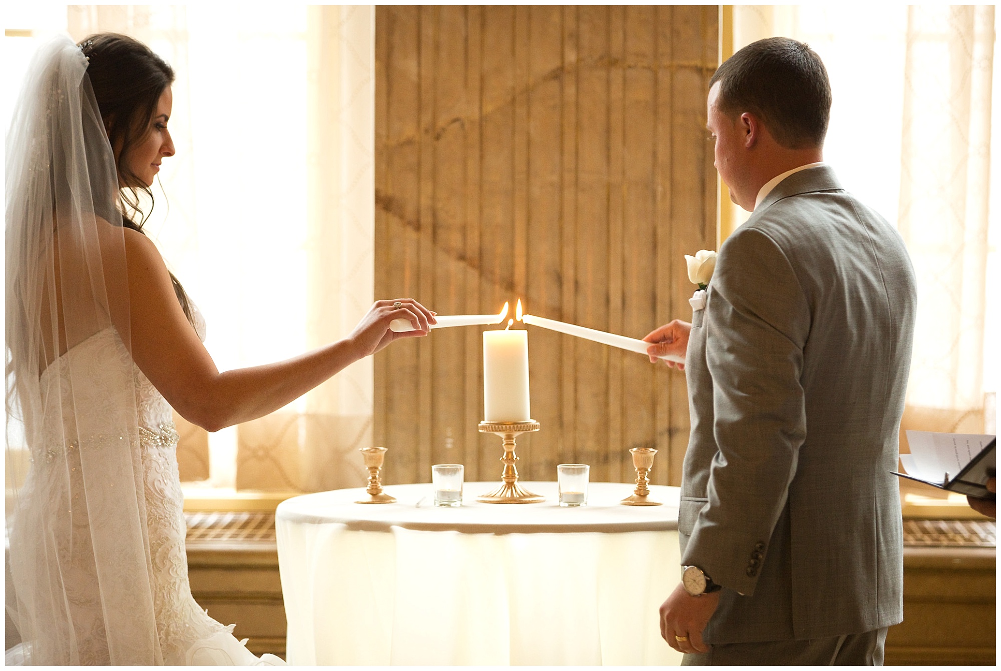 Photo of a bride and groom light a unity candle during their ceremony.