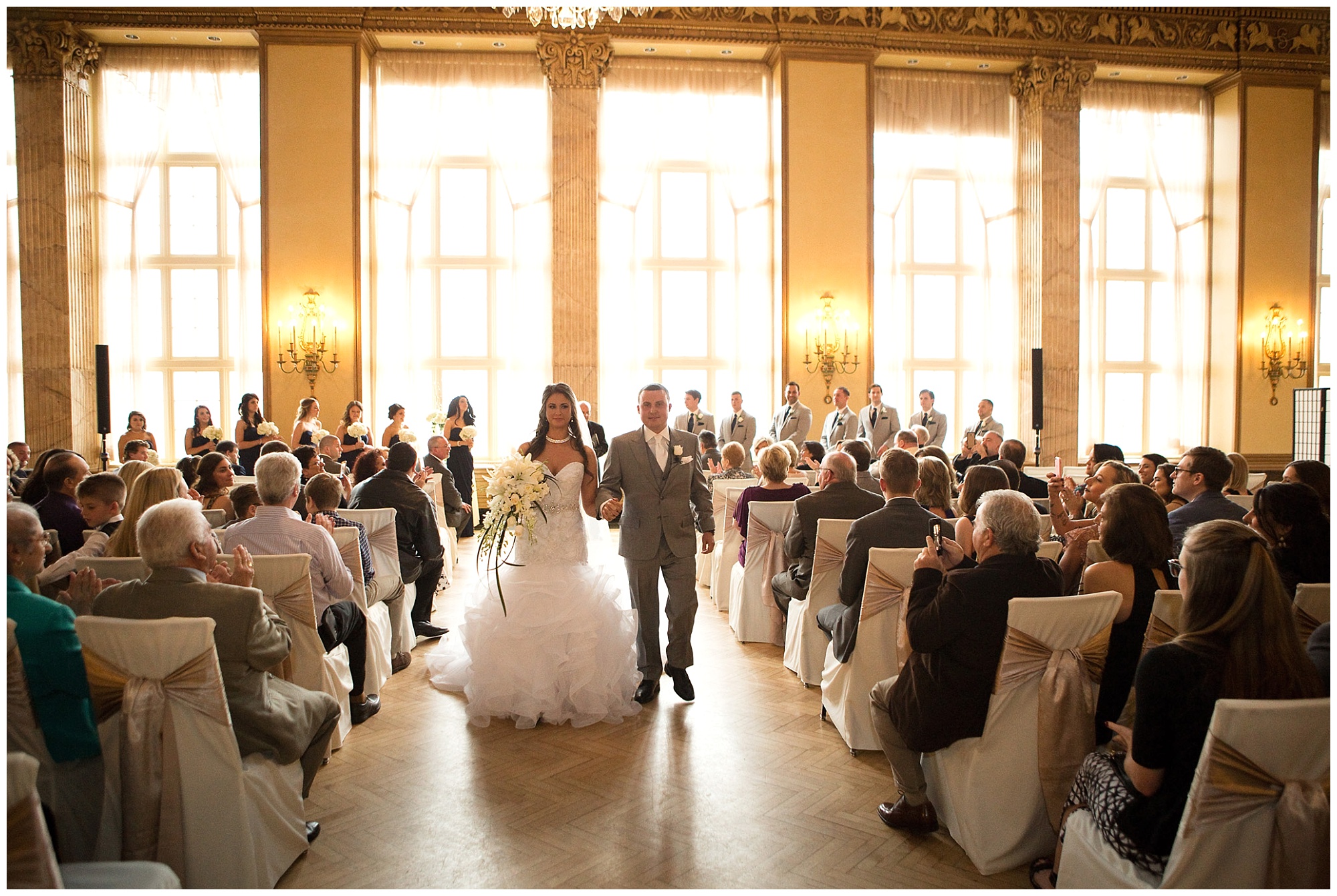 Photo of a bride and groom holding hands during their wedding ceremony recession.