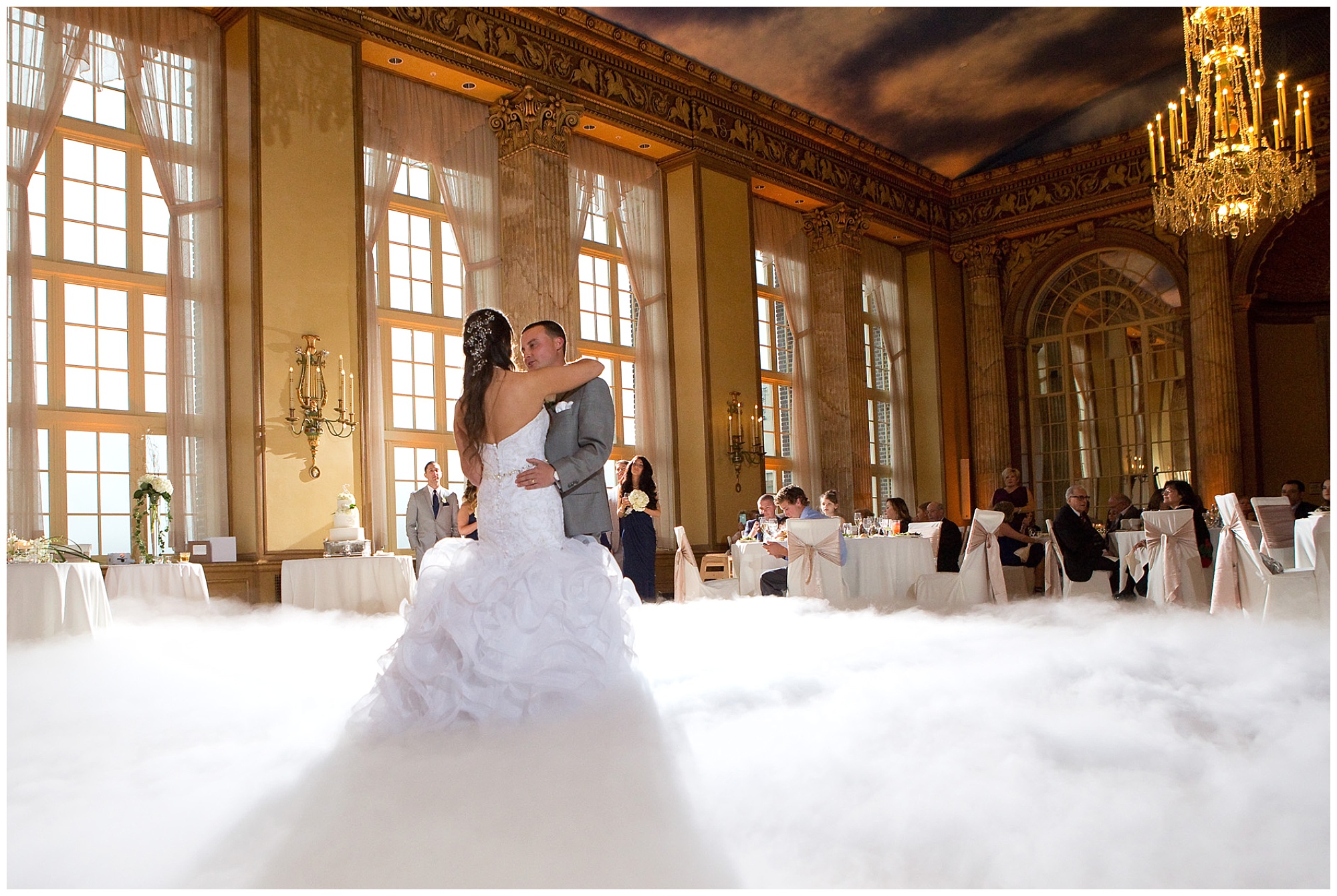 Photo of a bride and groom during their first dance as a dry ice cloud generator spills out a thick blanket of cloud over the dance floor.