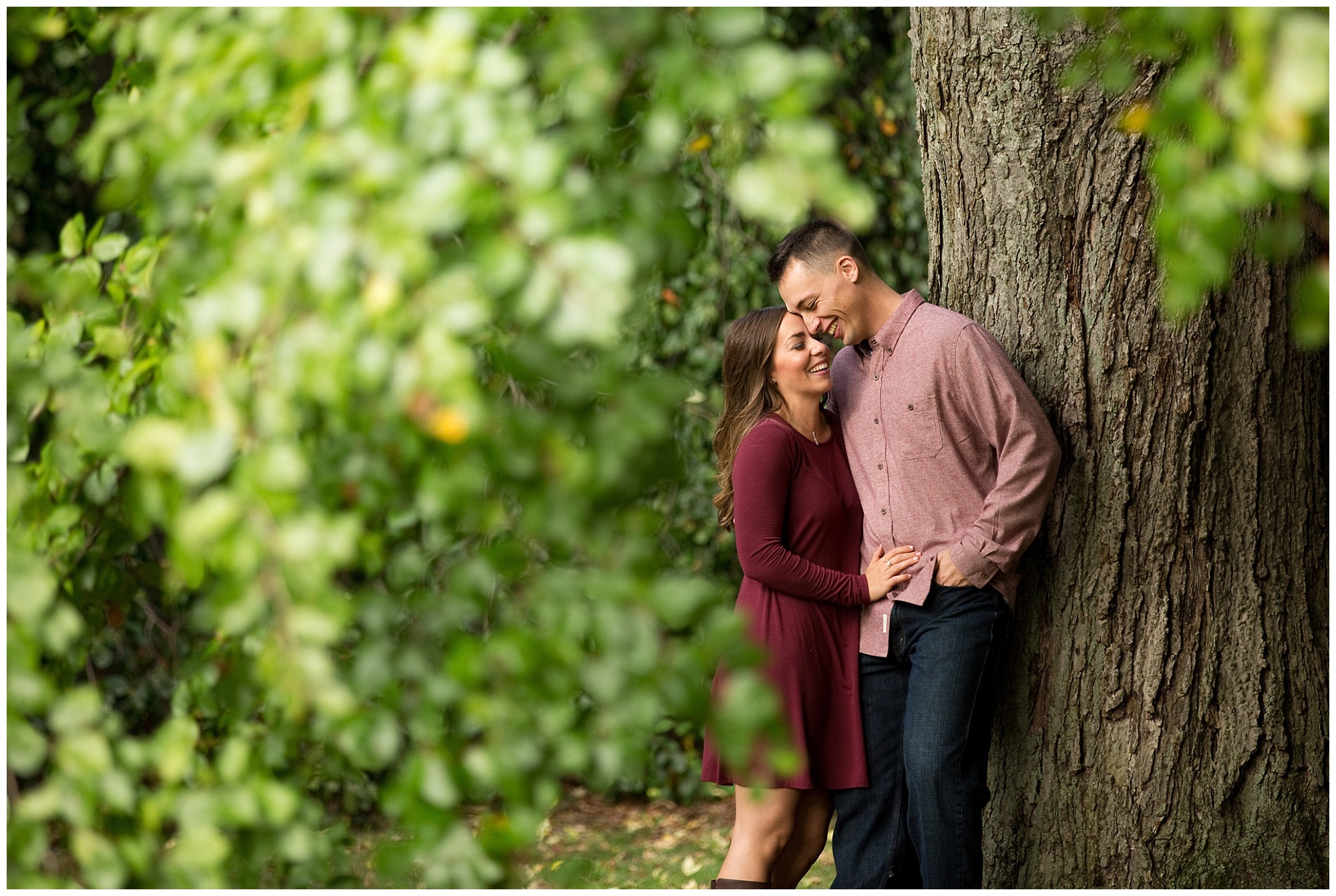 Photo of an engaged couple laughing togehter while under a tree.