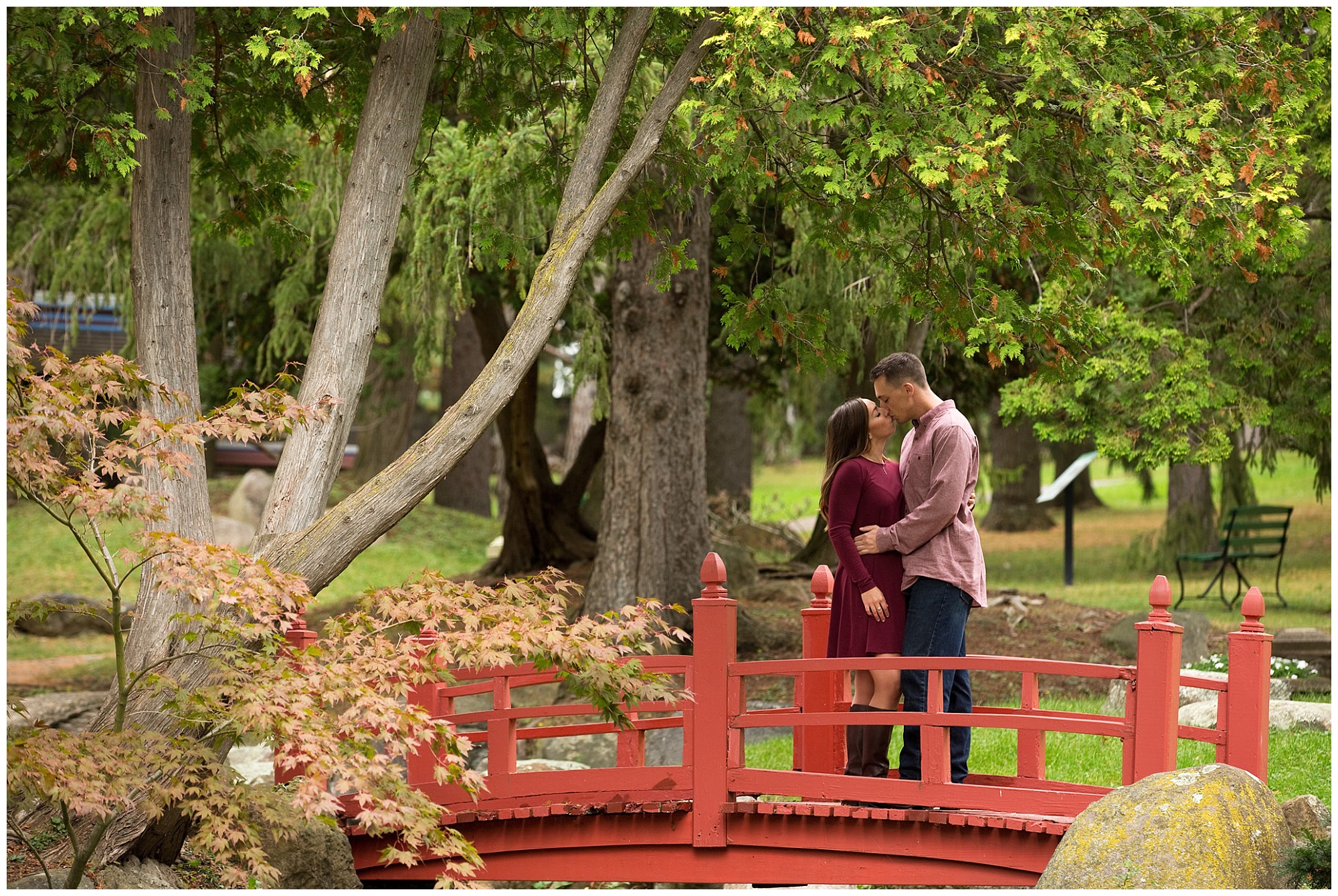 Photo of an engaged couple facing eachother while standing on a bridge in a Japanese garden.