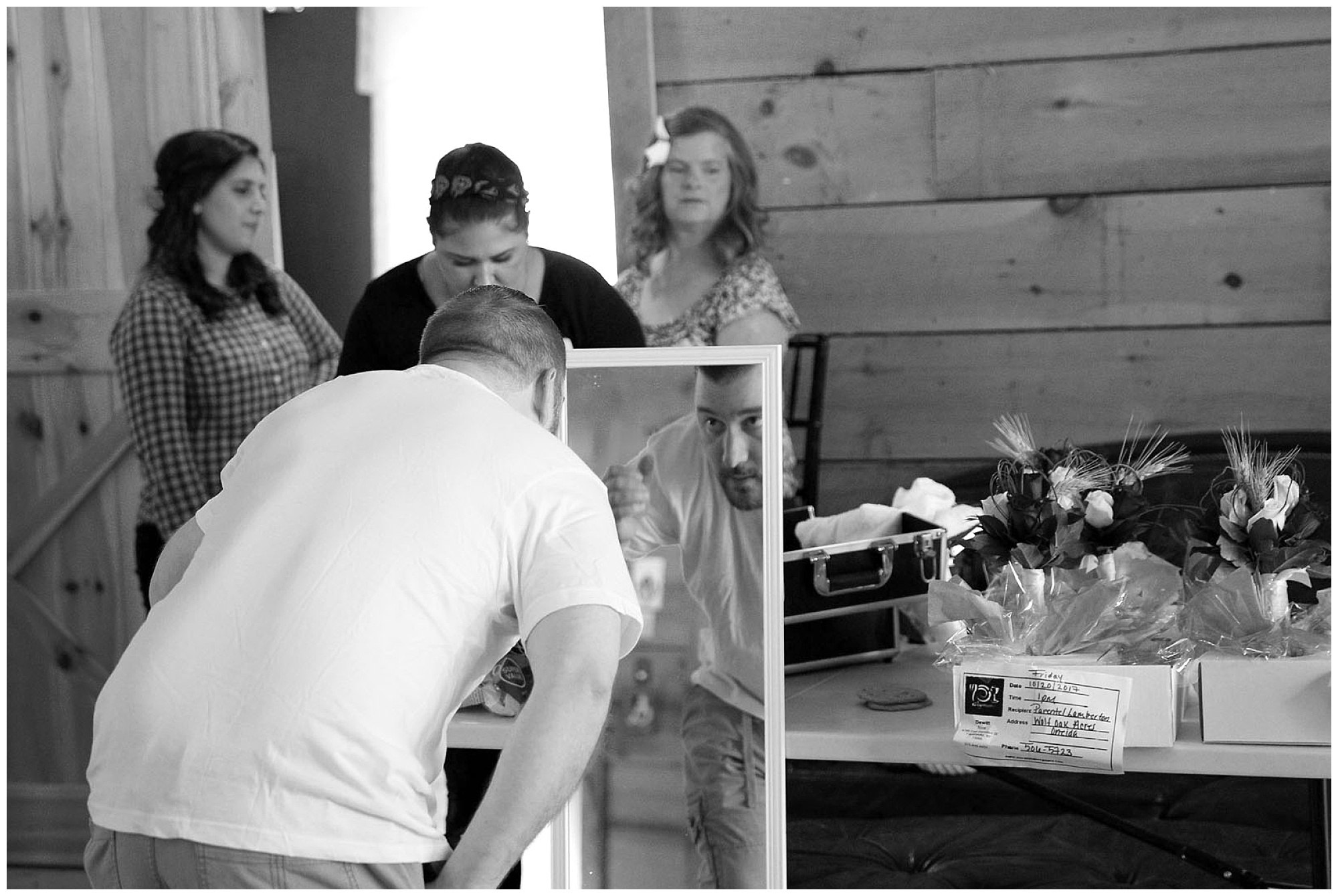 A photo of a groom looking into a mirror prior to his wedding.