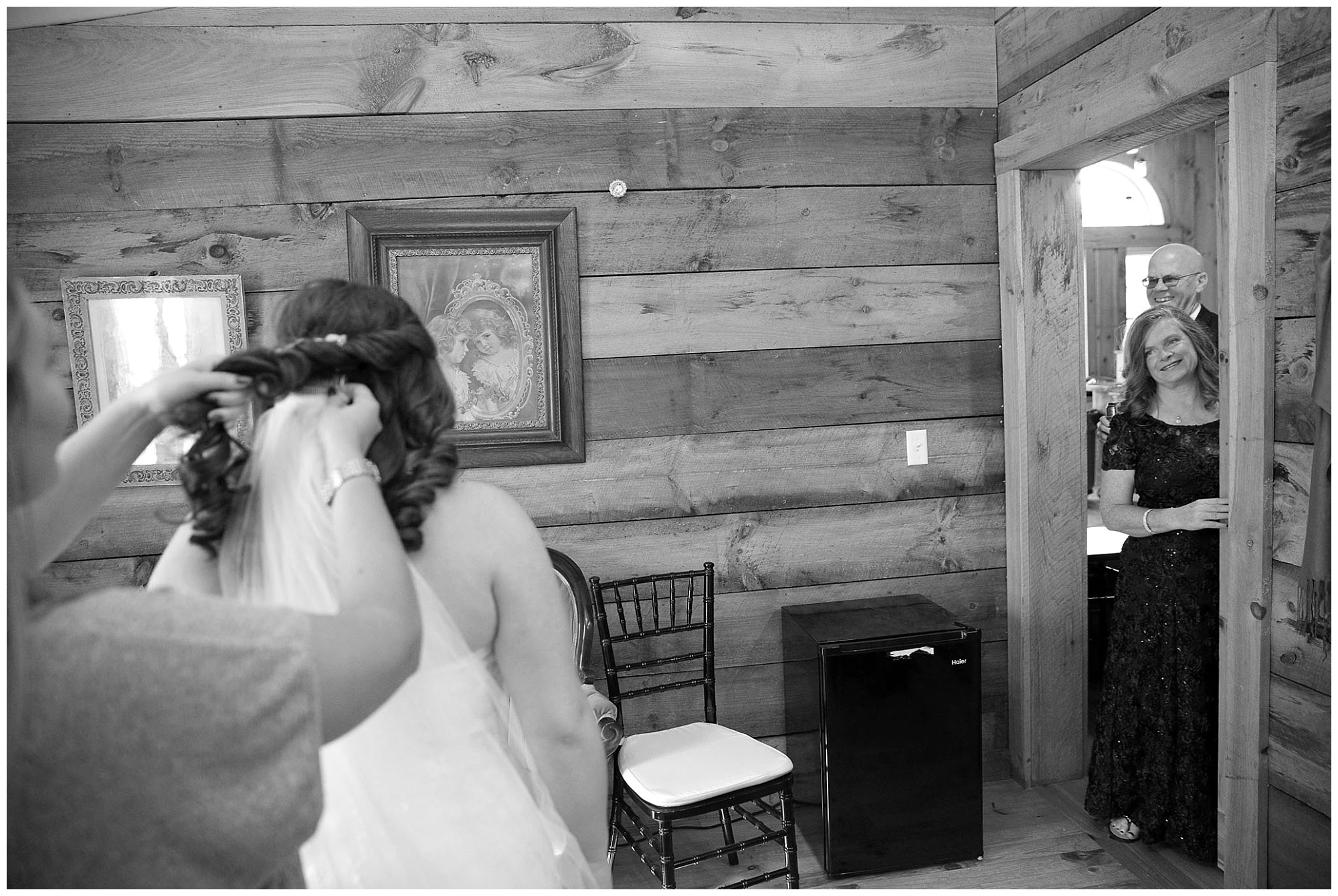 Photo of a bride's parents peeking at her from the room's door.
