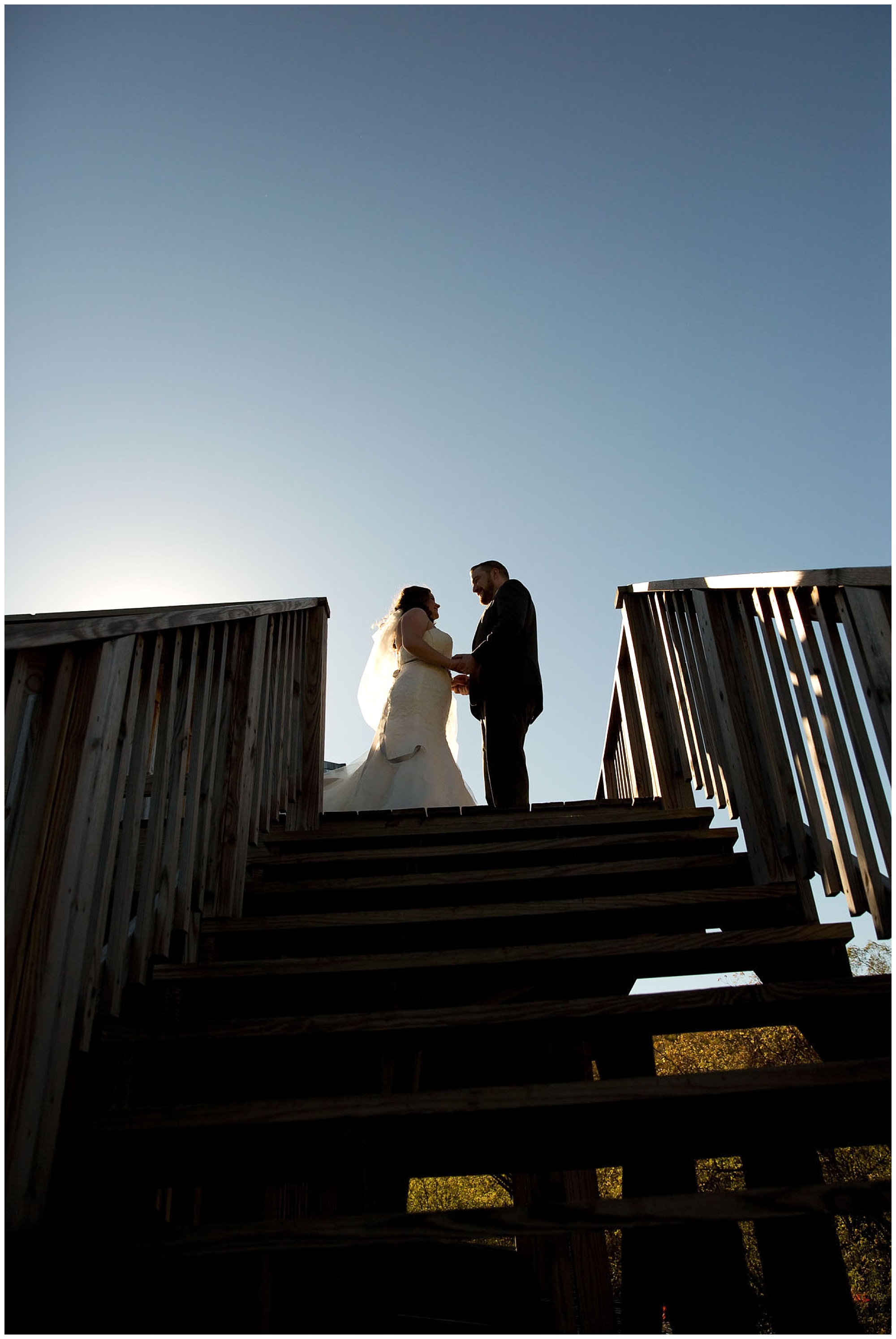 A silhouette photo of a bride and groom atop a deck stairway