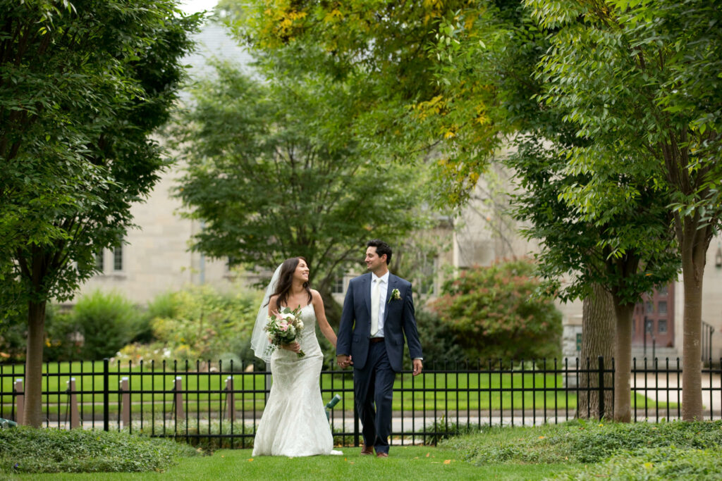 Bride and groom walking hand in hand smiling at each other