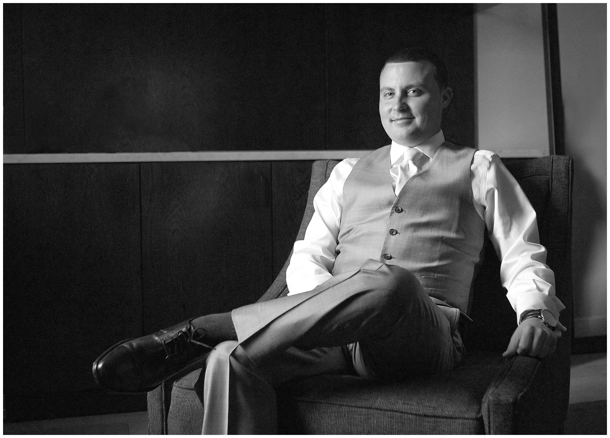 A portrait of a groom sitting in a chair waiting for ceremony time.