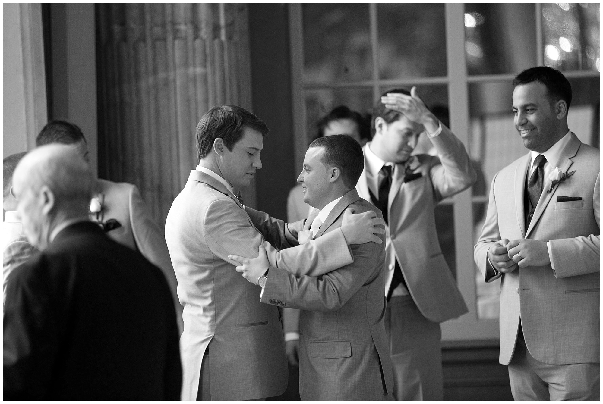 Photo of an arm embrace and meaningful look between a groom and his best man.